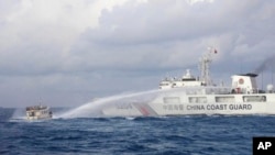 FILE - In this handout photo provided by the Philippine Coast Guard, a Chinese coast guard ship uses water cannons on Philippine navy-operated supply boat M/L Kalayaan as it approaches Second Thomas Shoal in the disputed South China Sea on Dec. 10, 2023.