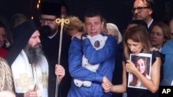 Parents of Ema Kobiljski, 13, mourn during the funeral procession at the central cemetery in Belgrade, Serbia, May 6, 2023. Police said that her schoolmate, a 13-year-old boy, used his father's guns to kill eight fellow students and a guard on Wednesday.