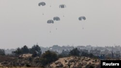 Humanitarian aid falls through the sky toward the Gaza Strip after being dropped from an aircraft, amid the ongoing conflict between Israel and the Palestinian Islamist group Hamas, as seen from Israel, March 28, 2024. 
