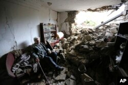 Seorang pria lanjut usia duduk di dalam rumah yang rusak setelah penembakan yang menurut pejabat Rusia di Donetsk dilakukan oleh pasukan Ukraina, di Donetsk, ibu kota wilayah Donetsk yang dikuasai Rusia, Ukraina timur, 28 April 2023. (Foto: AP)