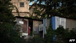 Une femme se tient devant la porte d'une maison dans un bidonville du quartier "Talus 2" à Koungou avant sa démolition sur l'île française de Mayotte, dans l'océan Indien, le 21 mai 2023.