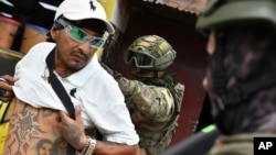 A soldier examines the back of a man, checking for gang tattoos, during a stop-and-frisk operation in Portoviejo, Ecuador, Jan. 11, 2024. 
