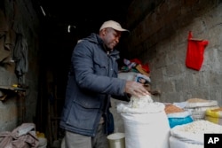 Vendor Francis Ndege measures rice at his stall in the Toi Market, Nairobi, Kenya on Wednesday, Aug. 9, 2023. (AP Photo/Brian Inganga)