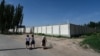 FILE - Children pass an old detention center near Kashgar, China, July 15, 2023. Since 2017, more than a million Uyghurs and other Muslims have been swept into internment camps. Beijing says inhabitants "graduated' and left after learning job skills.