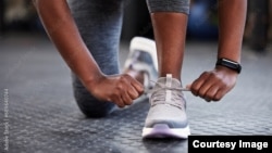 A woman ties up her shoestrings on her sneakers. (Adobe stock image)