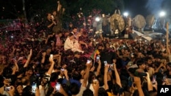 Supporters throw rose petals toward a vehicle carrying Pakistan's former Prime Minister Imran Khan to greet him upon his arrival at his home in Lahore, Pakistan, May 13, 2023. 