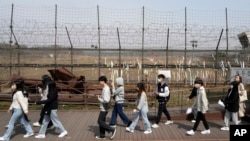 FILE - People pass by a wire fence at the Imjingak Pavilion in Paju South Korea, near the border with North Korea, March 24, 2023. 