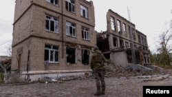 A police officer stands in front of a damaged building, amid Russia's attack on Ukraine, in the town of Avdiivka, Donetsk region, Ukraine, Oct. 17, 2023. 