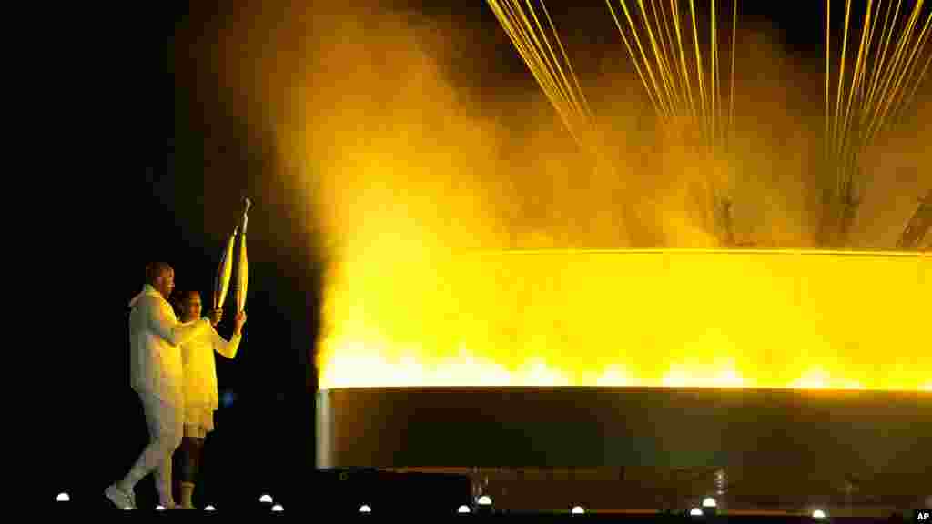 Former French Olympians Marie-Jose Perec, right, and Teddy Riner light the cauldron during the opening ceremony of the 2024 Summer Olympics in Paris, July 26, 2024.