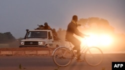 Un homme passe devant des gendarmes sur la route menant à la caserne militaire de la garde présidentielle d'élite (RSP), le 29 septembre 2015 à Ouagadougou, au Burkina Faso.