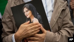 FILE - A person holds a portrait of Mahsa Amini during a rally in Washington on Oct. 1, 2022. Protesters called for regime change in Iran following the death of Amini, a woman who died after being arrested in Tehran by "morality police."