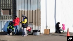 FILE - Immigrants stand outside a shelter in the Pilsen neighborhood of the city of Chicago, Illinois, Dec. 19, 2023. Across Chicago, Black residents are frustrated that their long-standing needs are not being met while the needs of the city's newly arrived are met with urgency.