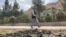 FILE - A man walks past the site of a suicide attack along the roadside in Faizabad district of Badakhshan province on June 6, 2023.