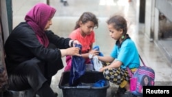 가자지구 중부 데이르 알-발라에서 팔레스타인 난민 가족이 유엔 팔레스타인난민구호기구(UNRWA) 산하 학교 부근 피난처에서 빨래를 하고 있다.