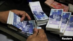 FILE - An employee counts Pakistani rupee notes at a bank in Peshawar, Pakistan, Aug. 22, 2023. Pakistan launched a crackdown in September 2023 to curb the illegal flight of the dollar in a bid to strengthen the weak rupee. 