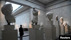 FILE - An employee views examples of the Parthenon sculptures, sometimes referred to in the UK as the Elgin Marbles, on display at the British Museum in London, Jan. 25, 2023. 