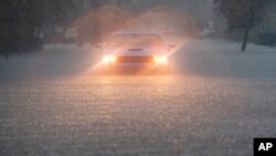 A driver blinks their hazard lights as heavy rain falls over parts of South Florida on June 12, 2024, in Hollywood, Fla.