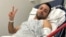 FILE - Pouria Zeraati, a presenter for independent Persian-language outlet Iran International, flashes a victory sign in a photo he posted of himself on X March 30, 2024, while hospitalized after a stabbing attack.