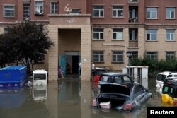 People stay on a roof at a flooded residential compound after the rains and floods brought by remnants of Typhoon Doksuri, in Zhuozhou, Hebei province, China, Aug. 3, 2023.