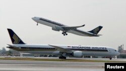 Sebuah pesawat Airbus A330-300 milik Singapore Airlines lepas landas di belakang pesawat Boeing 787-10 Dreamliner milik Singapore Airlines di Bandara Changi, Singapura, 28 Maret 2018. (Foto: Edgar Su/Reuters)