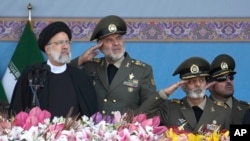 Iranian President Ebrahim Raisi, left, reviews an army parade commemorating Army Day in front of the mausoleum of the late revolutionary founder Ayatollah Khomeini just outside Tehran, April 18, 2023. 