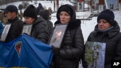 FILE - Relatives of Ukrainian soldiers who were captured by Russia hold their photos demanding they be freed, at a rally in central Kyiv, Ukraine, Dec. 10, 2023.