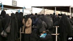 FILE - Female residents from former Islamic State-held areas in Syria line up for aid at al-Hol camp in Hasakeh province, Syria, March 31, 2019.