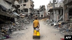 一名巴勒斯坦男子在加沙地带南部汗尤尼斯满是废墟的街道上拉着一辆手推车。（2024年5月2日）