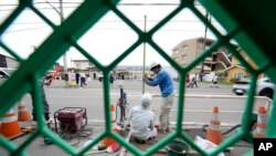 คนงานติดแผนกั้นใกล้ร้านสะดวกซื้อลอว์สัน เมื่อ 30 เม.ย. 2024 ในญี่ปุ่น ซึ่งเป็นแลนด์มาร์คถ่ายภาพภูเขาไฟฟูจิ หลังนักท่องเที่ยวแห่เยือนจนล้นพื้นที่ (AP Photo/Eugene Hoshiko)