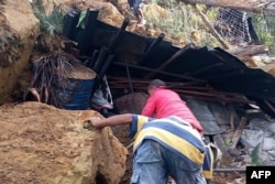 Penduduk setempat melihat ke dalam rumah yang hancur di lokasi longsor di Desa Yambali di wilayah Maip Mulitaka, di Provinsi Enga, Papua Nugini pada 25 Mei 2024. (Foto: AFP)