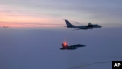 FILE - In this March 9, 2020, photo released by the North American Aerospace Defense Command (NORAD), a Russian Tu-142 maritime reconnaissance aircraft, top, is intercepted near Alaska. NORAD said it tracked two Russian and two Chinese aircraft off the coast of Alaska.