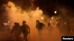 FILE - French CRS riot police run amid clashes with protesters during a demonstration as part of the ninth day of nationwide strikes and protests against French government's pension reform, in Paris, March 23, 2023. 