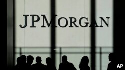 FILE - People are silhouetted under a JPMorgan Chase & Co. logo at the bank's headquarters in New York City, Oct. 21, 2013.