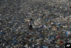 FILE - A boy walks on the plastic waste at the Badhwar Park beach on the Arabian Sea coast in Mumbai, India, June 5, 2023.