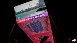 A man walks by a large screen at a shopping mall showing CCTV broadcasting news of the Fukushima Daiichi nuclear power plant began releasing its first batch of treated radioactive water into the Pacific Ocean, in Beijing, Aug. 24, 2023. 