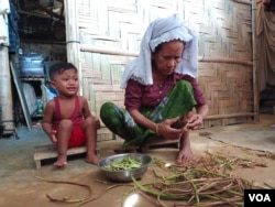 A Rohingya woman readies stems of a wild plant before cooking them at her home in Balukhali camp, Cox’s Bazar, Bangladesh, on July 22, 2023. (Noor Hossain for VOA)