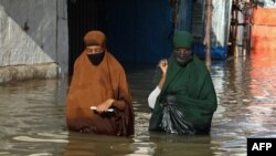 Women walk through floodwater in Beledweyne, Somalia, May 12, 2023. The Shabelle River burst its banks in Beledweyne, forcing thousands of people to abandon their homes, according to the United Nations Office for the Coordination of Humanitarian Affairs. 