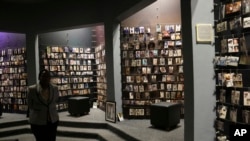 FILE - A tourist walks past family photos of victims in an exhibition at the Kigali Genocide Memorial in Kigali, Rwanda, April 4, 2024. Emmanuel Nkunduwimye, 65, was sentenced to prison June 10, 2024, in Brussels for murder and rape committed during the 1994 Rwandan genocide.
