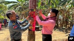 An animal health officer and a military police officer place posters about awareness of H5N1 virus threats in Prey Veng eastern province Cambodia, Thursday, Feb. 23, 2023. (Cambodia Ministry of Health via AP)