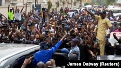 Bola Ahmed Tinubu (en bleu, de dos) salue ses partisans après avoir voté à Ikeja, Lagos, Nigeria le 25 février 2023. 