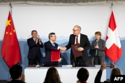 Swiss Economy Minister Guy Parmelin and Wang Shouwen, Chinese Vice Minister of the Ministry of Commerce, shake hands after signing a joint statement of the free trade agreement, in Kehrsatz, near Switzerland's administrative capital Bern, Jan. 15, 2024.