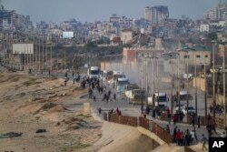 Palestinians gather around trucks loaded with humanitarian aid brought in through a new U.S.-built pier, in the central Gaza Strip, May 18, 2024.