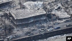 Wildfire wreckage is shown Aug. 10, 2023, in Lahaina, Hawaii. Residents crossed the wall into the ocean to escape the fire that was moving through the community.