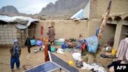 An Afghan man collects his belongings inside the courtyard of his damaged house following heavy rains and flash flooding, in Kandahar on April 14, 2024. 