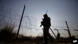 FILE - An Indian soldier patrols along the India-Pakistan international border in Kathua district, Dec. 6, 2013.