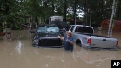 A man waves at Texas Parks & Wildlife Department game wardens as they arrive by boat to rescue residents from floodwaters, in Liberty County, Texas, May 4, 2024.
