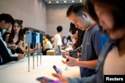 Para pengunjung mengamati iPhone 15 Pro baru yang secara resmi mulai dijual di seluruh China di sebuah toko Apple di Shanghai, China, 22 September 2023. (REUTERS/Aly Song)