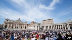 People gather in St. Peter's Square at the Vatican as Pope Francis recites the Angelus noon prayer from the window of his studio, Aug. 27, 2023.