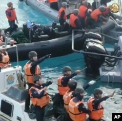 Penjaga Pantai China memegang pisau dan parang saat mendekati pasukan Filipina dalam misi pasokan di Beting Second Thomas, Laut Cina Selatan yang disengketakan, 17 Juni 2024. (Angkatan Bersenjata Filipina via AP)