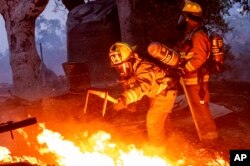 Firefighters extinguish a burning outbuilding as the Point Fire spreads along West Dry Creek Road in Healdsburg, California, June 16, 2024.